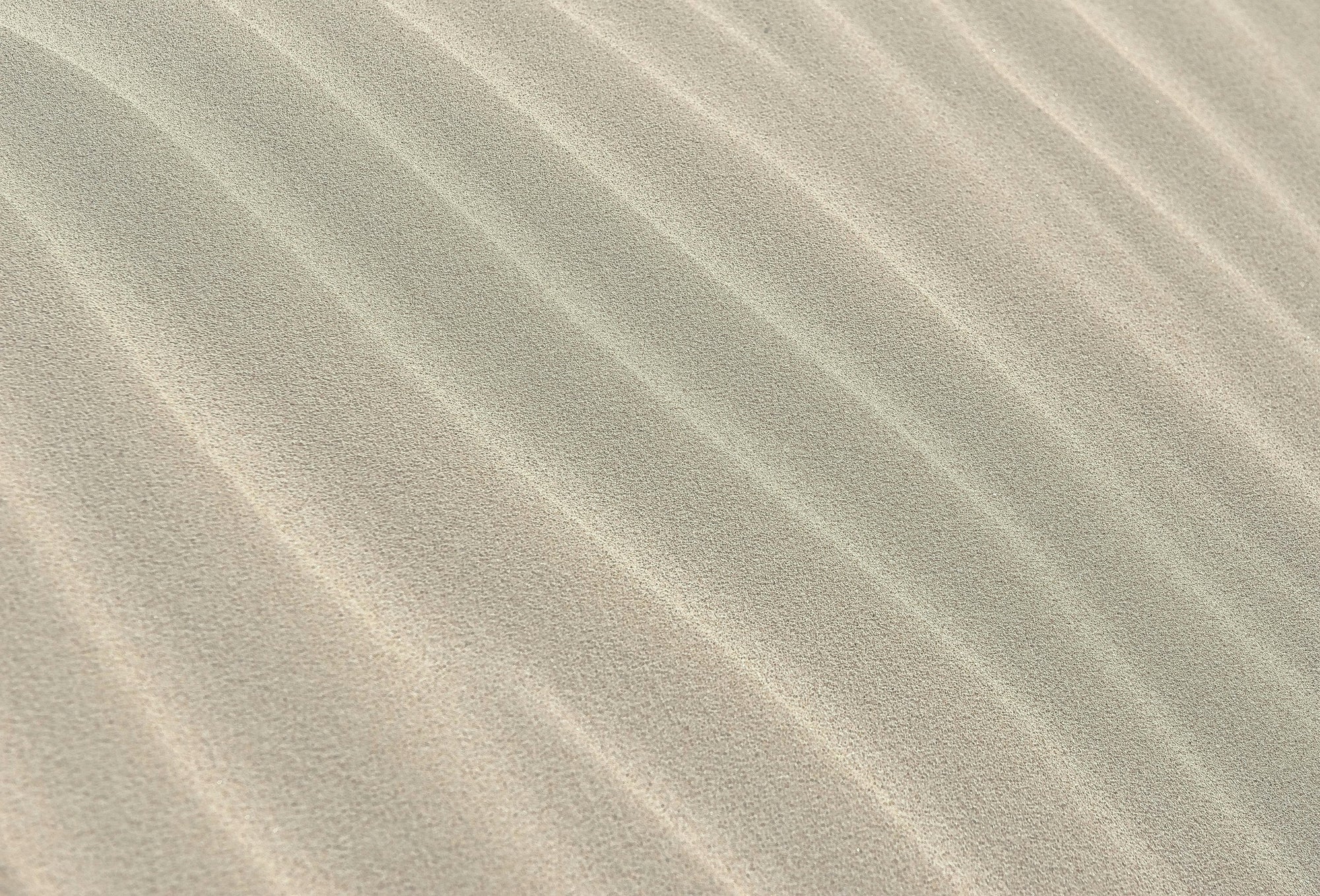 Close-up of sand dunes with ripples in a desert landscape. Textured close-up of golden sand, used as a calming natural background representing purity and earth-derived wellness.